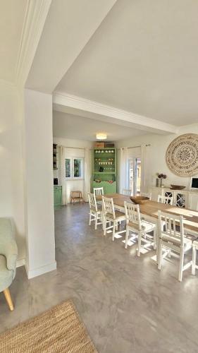 a dining room with white chairs and a table at Yellow House Ericeira in Santo Isidoro