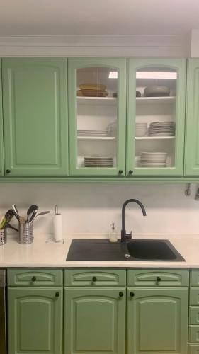 a kitchen with green cabinets and a sink at Yellow House Ericeira in Santo Isidoro