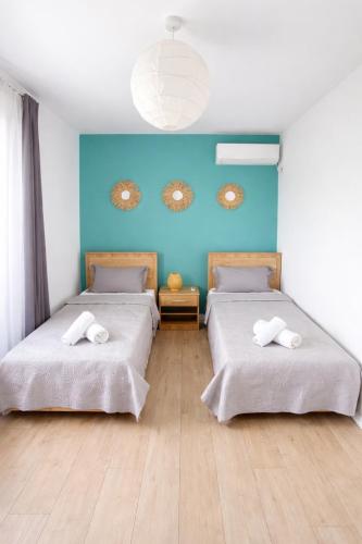 two beds in a room with a blue wall at Villa Marea Private Pool in Grand Baie with garden, BBQ & Parking in Grand-Baie