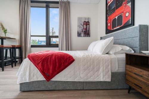a bedroom with a bed with a red blanket on it at Bridge View at The MillRows Suites in New Glasgow