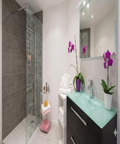 a bathroom with a sink and a shower with purple flowers at La Roche aux Fées in Lapte