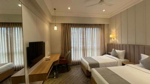 a hotel room with two beds and a desk and a television at Hotel Mumbai House Mindspace Malad in Mumbai