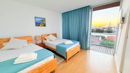 a hotel room with two beds and a balcony at Marina Mar II Premium in Vila Franca do Campo