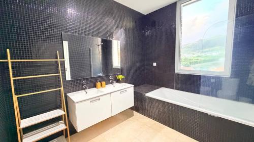 a bathroom with a sink and a tub and a window at Marina Mar II Premium in Vila Franca do Campo