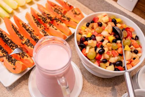 a table with a bowl of fruit and a bowl of milk at Hotel Vila Verde in Nova Friburgo