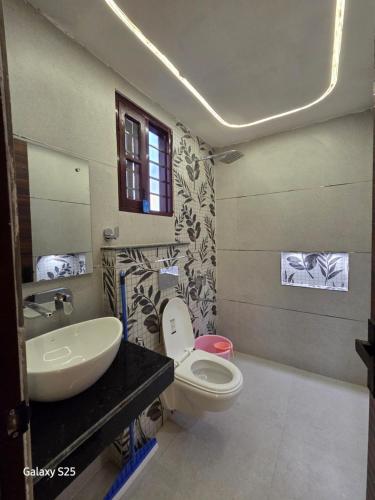 a bathroom with a white toilet and a sink at Eknav Villa in Kharar