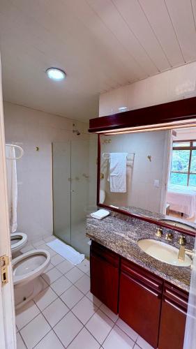 a bathroom with a toilet and a sink and a mirror at Suite master, condo-hotel in Joinville