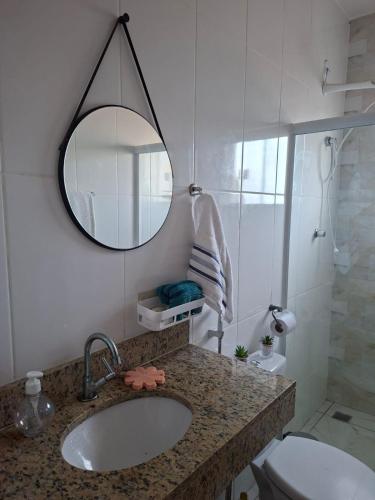 a bathroom with a sink and a mirror and a toilet at Aconchego em Maricá in Maricá