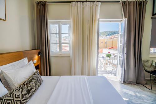 a bedroom with a bed and a view of a balcony at OIKO MINI SUITES in Ermoupoli