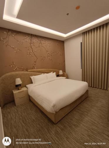 a bedroom with a large white bed and a night stand at Pure Stay House in Taif