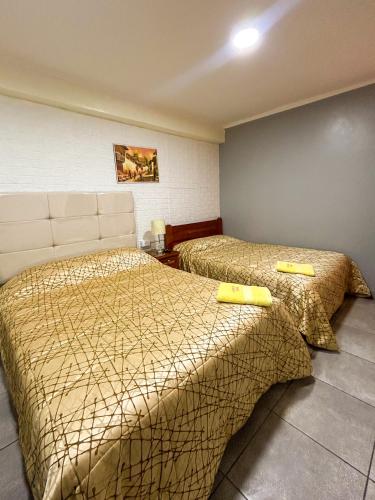 a hotel room with two beds with yellow comforter at Hotel Virgen del Carmen - Huaraz in Huaraz