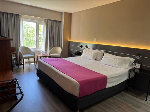 a hotel room with a large bed with a pink blanket at Quorum Córdoba Hotel, Resort Urbano in Córdoba