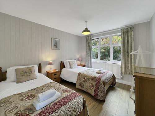 a bedroom with two beds and a window at West Wind Porlock in Porlock