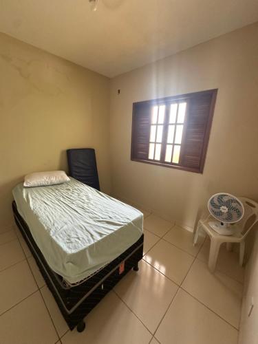 a bedroom with a bed and a chair and a window at Apt Pituba 500m Praia in Itacaré