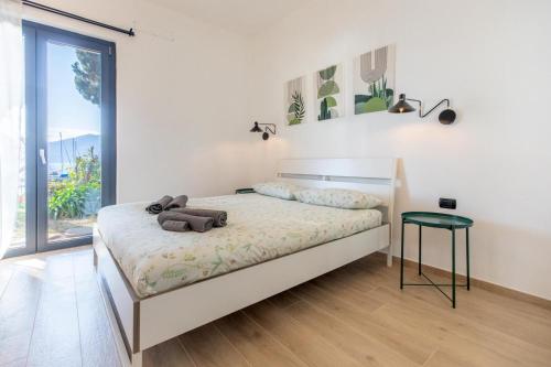 a white bedroom with a bed with a green stool at Gli Oleandri in Bellano