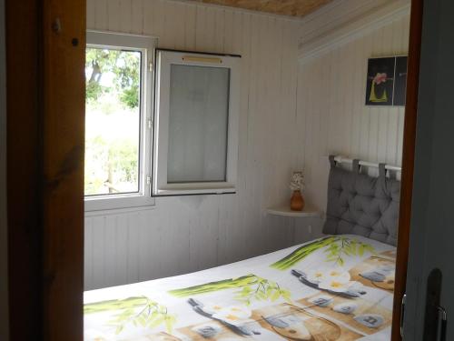 a bed in a bedroom with a window and a bedspread at chalet nature 2 in Aspiran