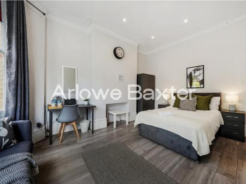a bedroom with a bed and a desk and a clock at Hackney Guest Rooms in London