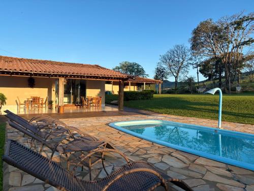 a patio with a pool and chairs and a house at Pousada Império de Minas in Capitólio