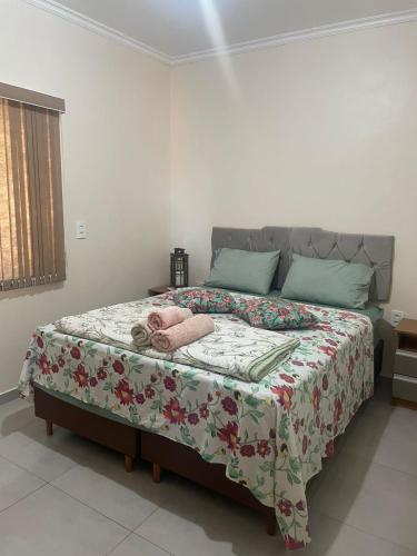 a bedroom with a large bed with a floral blanket at Apartamento Aconchegante 2 Quartos in Tabapira