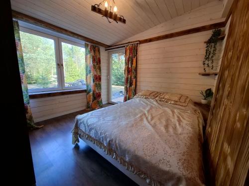a bedroom with a bed in a room with windows at Leśna chatka in Wilga