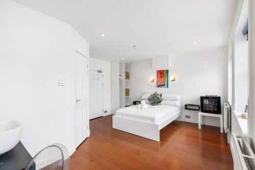 a white bedroom with a bed and a television at Orien tal By My Getaways in Brighton & Hove