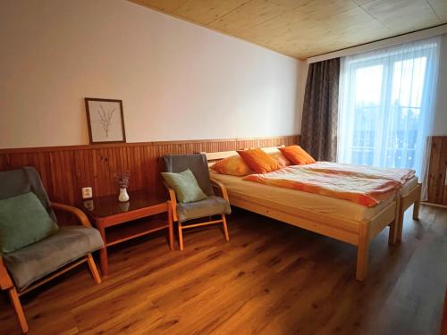 a bedroom with a bed and two chairs and a window at Penzion U Kuboňů in Volary