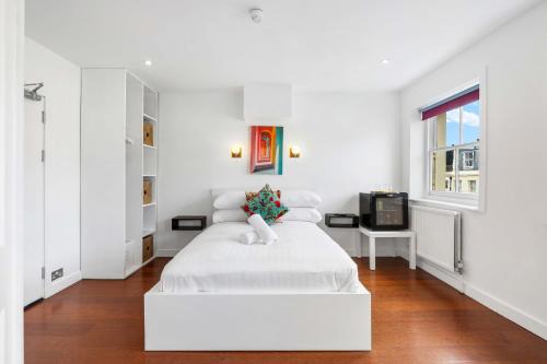 a white bedroom with a white bed and a television at Orien tal By My Getaways in Brighton & Hove