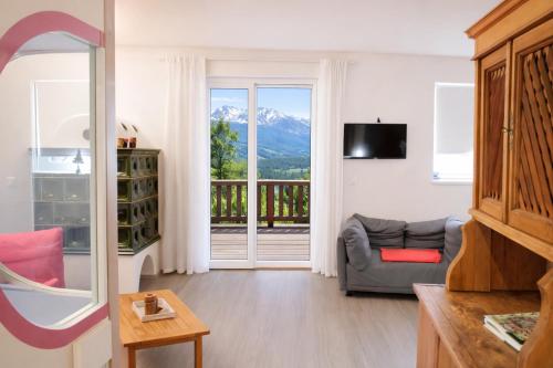 a living room with a couch and a sliding glass door at CASA 4 PIOPPI - Vista Lagorai e tranquillità a Cavalese - Dolomiti Affitti in Cavalese