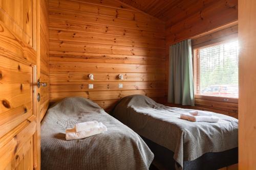 a bedroom with two beds in a wooden cabin at Mökki Vierumäki in Myllykylä