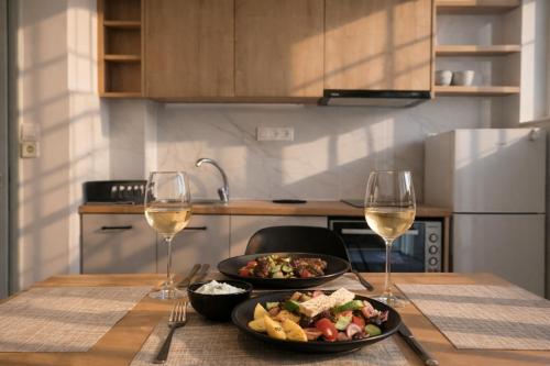 a table with two plates of food and two glasses of wine at Mardinik Hotel Apartments in Rethymno
