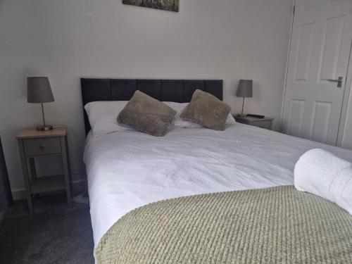 a white bed with two pillows on top of it at 5 bedroom house - Cheshire Oaks in Ellesmere Port