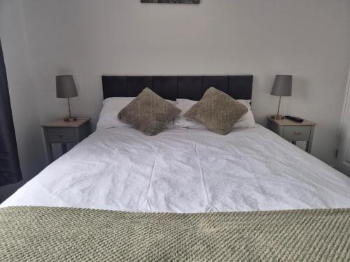 a white bed with two nightstands and two lamps at 5 bedroom house - Cheshire Oaks in Ellesmere Port