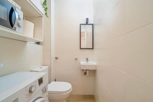 a white bathroom with a toilet and a sink at The Art Flat in Figueres