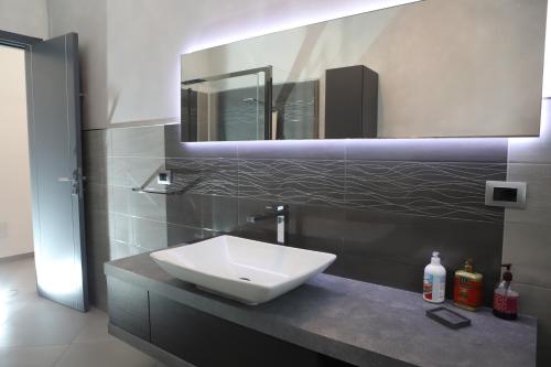 a bathroom with a white sink and a mirror at Mandrolisai Rooms in Samughèo