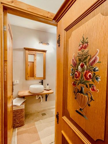 a bathroom with a wooden door with a vase on it at Sadova Village - Casa Maria in Sadova
