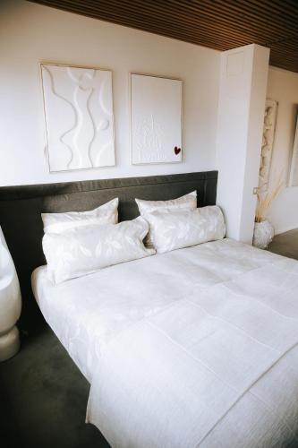 a large bed with white sheets and pillows at The living gallery in Roja