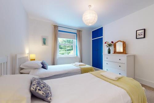 a bedroom with three beds and a window at High Bank Porlock in Porlock
