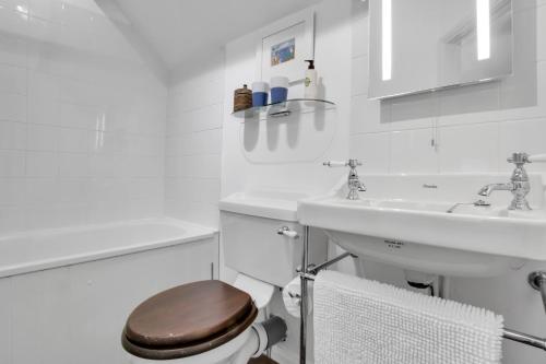a white bathroom with a toilet and a sink at Cascade Cottage Exford in Exford