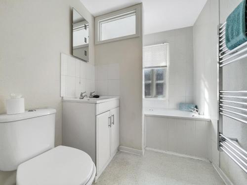 a white bathroom with a toilet and a sink at Grace Cottage Porlock in Porlock