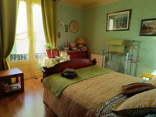 a bedroom with a bed with green walls and a window at Chambres d'hôtes Chez nous in Nantheuil