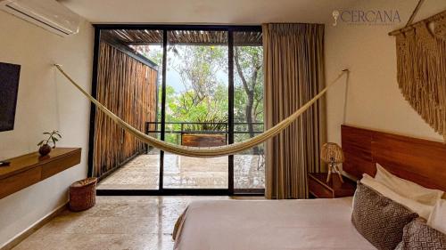 a bedroom with a hammock in front of a large window at Amaka Calma Tulum by Cercana in Tulum