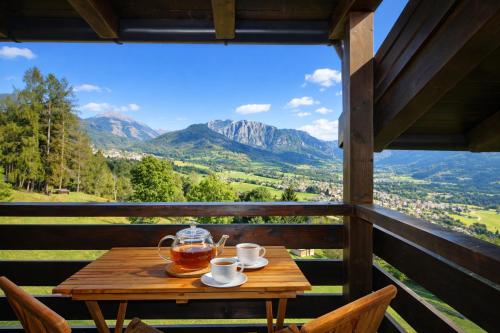 a table with two cups of tea on a balcony with mountains at SKYWAY LOFT - Residence Veronza con piscina, Dolomiti Affitti in Cavalese