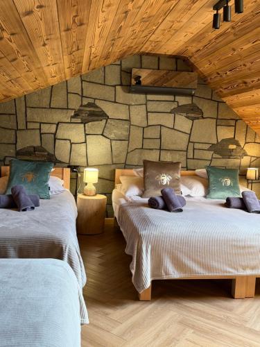two beds in a room with a stone wall at Apartamenty Stylo in Istebna