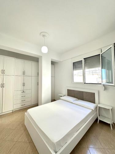 a white bedroom with a large bed and windows at Spacious Lovely Apartment in Sarandë
