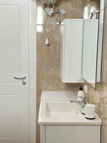 a white bathroom with a sink and a shower at Spacious Lovely Apartment in Sarandë