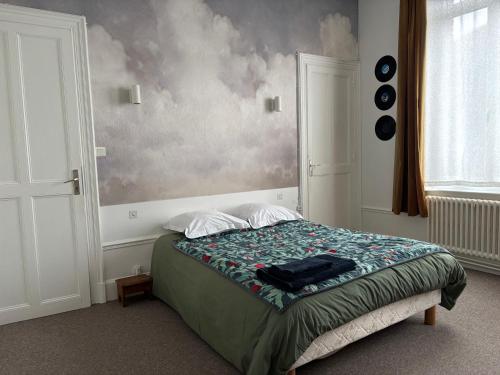 a bedroom with a bed and a painting on the wall at Maison Dentelle in Caudry