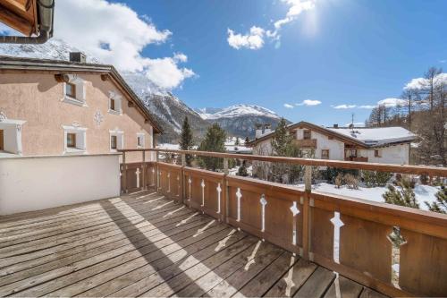a balcony with a wooden deck with mountains in the background at Luxury Chalet St Moritz with View - 4 Bedrooms in Madulain
