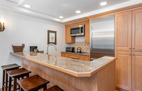 a kitchen with a stainless steel refrigerator and wooden cabinets at Christiania Condominiums- CoralTree Residence Collection in Vail