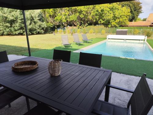 a wooden table with chairs and a swimming pool at Maison de vacances avec piscine in Soustons
