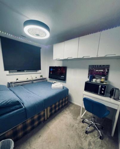 a bedroom with a bed and a desk and a television at Room 3 minute drive from Luton Airport in Luton